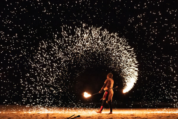 A fire dancer creates showers of sparks on Grace Bay Beach at night. 