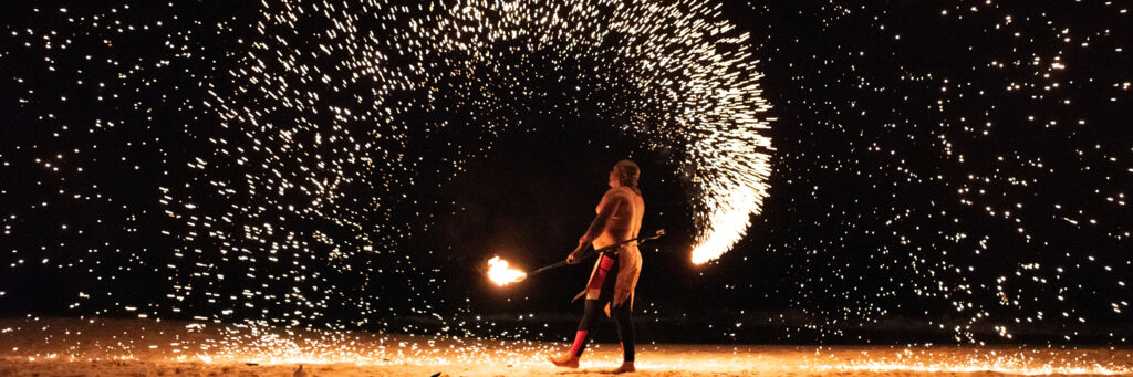 A fire dancer creates showers of sparks on Grace Bay Beach at night. 