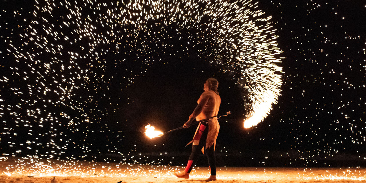 A fire dancer creates showers of sparks on Grace Bay Beach at night. 