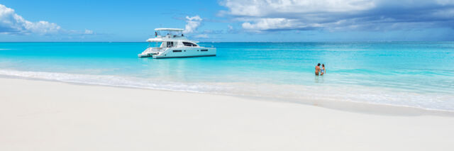 Yacht and couple at Water Cay beach in the Turks and Caicos