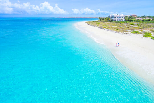 Aerial view of two people walking on the secluded Grace Bay Beach in the Turks and Caicos