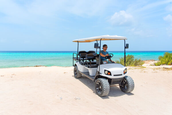 Man in a golf cart parked on a white-sand beach in Grand Turk