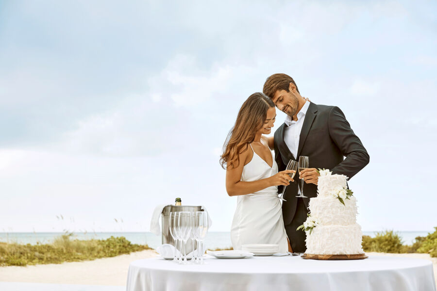 Newlywed couple in Turks and Caicos cutting cake on the beach.