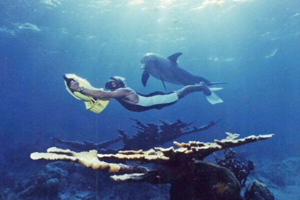 Vintage photo of a man snorkeling with a bottlenose dolphin on a coral reef