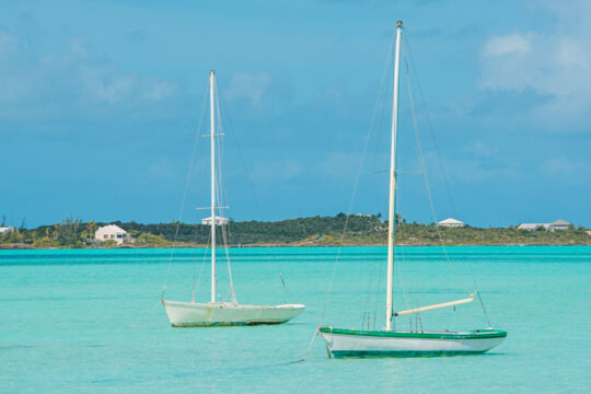 Two small Caicos Sloop sailboats anchored at the east side of Chalk Sound