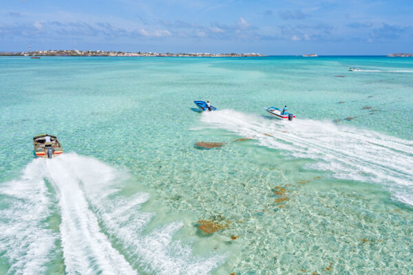 Aerial view of speed boats racing to a small cay. 