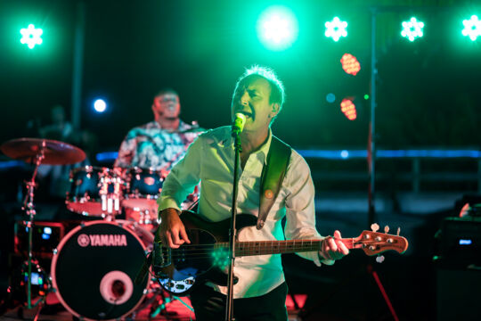 Bass guitarist singing on a stage at night