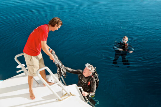 Diver climbing onto a liveaboard yacht in Turks and Caicos. 