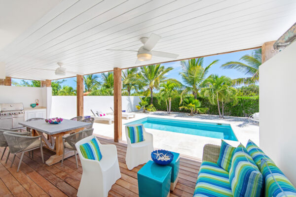 A covered porch with seating and an outdoor dining area at a villa in Providenciales. 