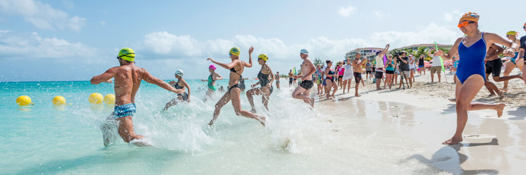 Open water swimmers running into the water on Grace Bay Beach. 