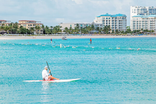 A stand-up paddleboarder supervising swimmers during Race for the Conch, Grace Bay Beach. 