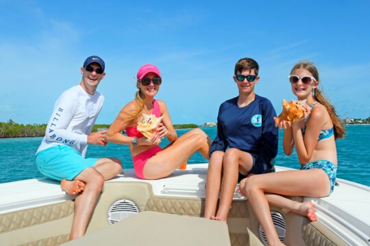 Family holding conch shells on a boat in the Turks and Caicos Islands.