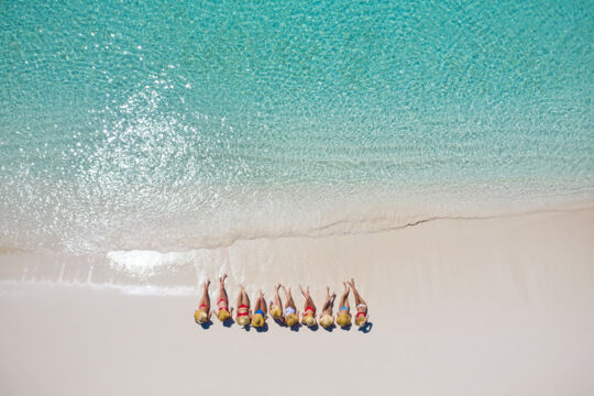 Group of women sitting on the beach at Water Cay, Turks and Caicos Islands.