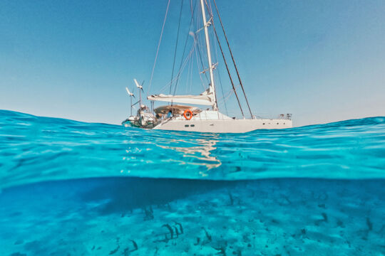 Under-over photo of a luxury catamaran cruising above the seabed in Turks and Caicos.