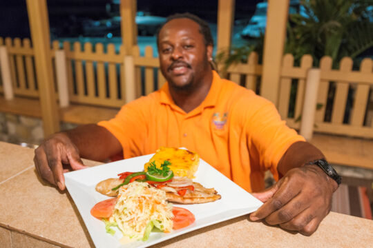 Chef with plate of fish and mac and cheese on South Caicos