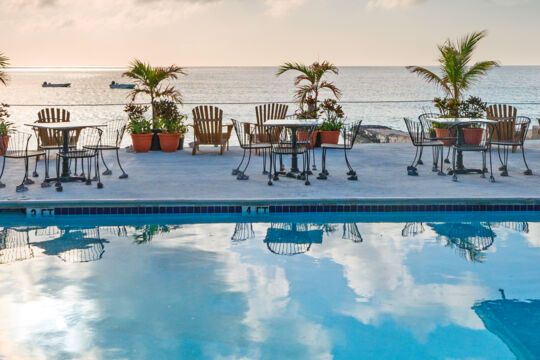 Bistro tables on a concrete deck overlooking the ocean at sunset