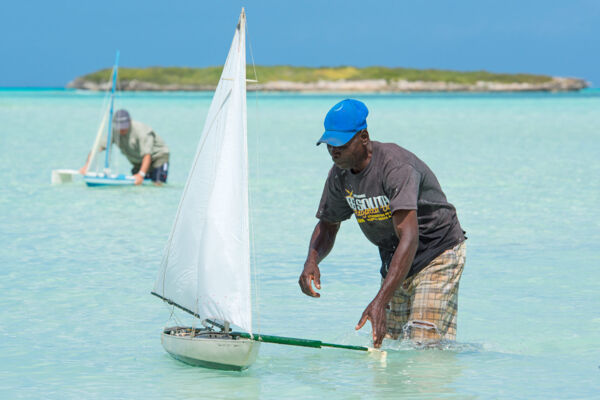 Man sailing a model sailboat at Bambarra Beach, Middle Caicos. 