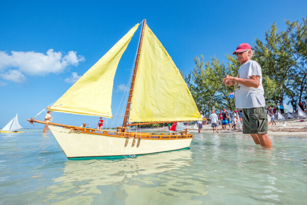 Yellow model sailboat with a crowd of people in the background on Middle Caicos.