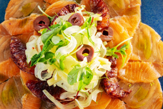 Overhead image of a colorful plate of salmon crudo, topped with oranges, from Vita restaurant.