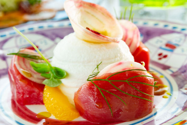 Artistic plate of bright red tuna tartar with avocado cream, fennel, orange, and basil. 